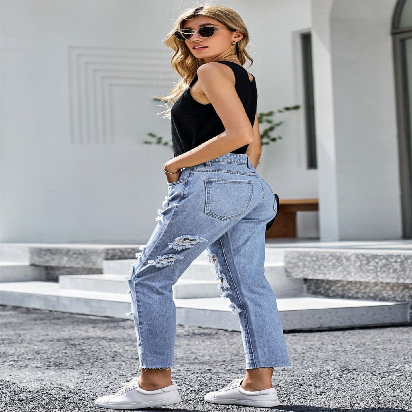 Woman wearing light blue jeans and a black top outdoors.
