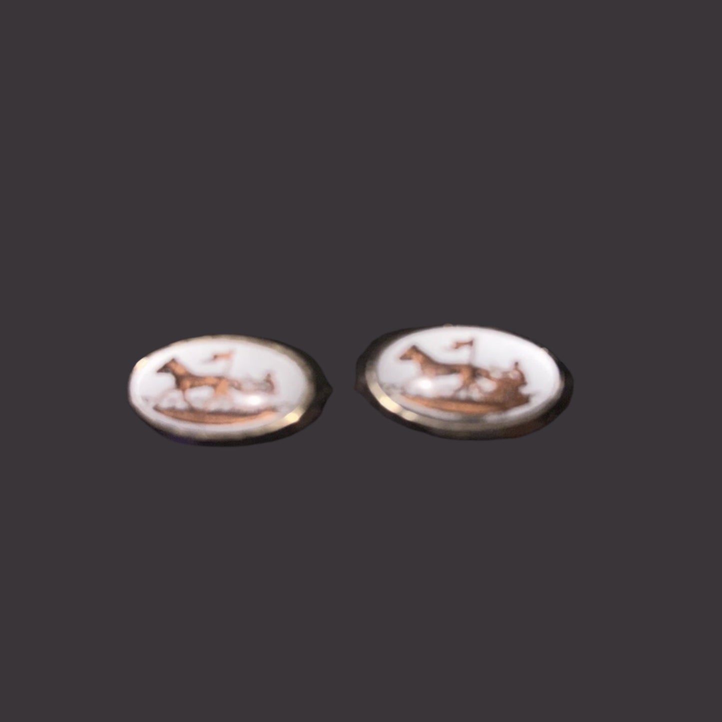 Pair of earrings with white stone and gold accents on a dark background