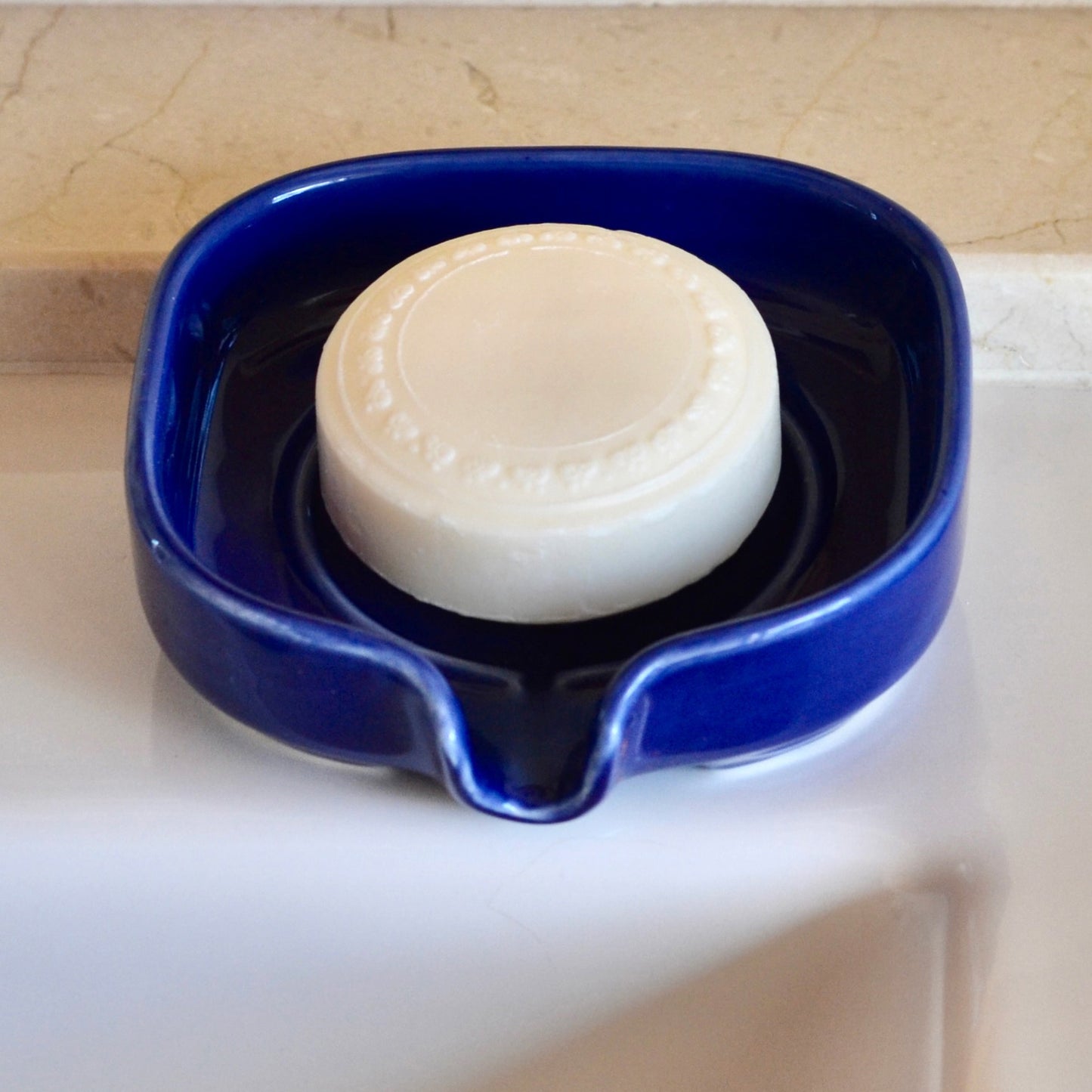 Elegant glossy blue color self-draining porcelain soap dish with a sloped design to keep soap dry and clean. Soap not included.