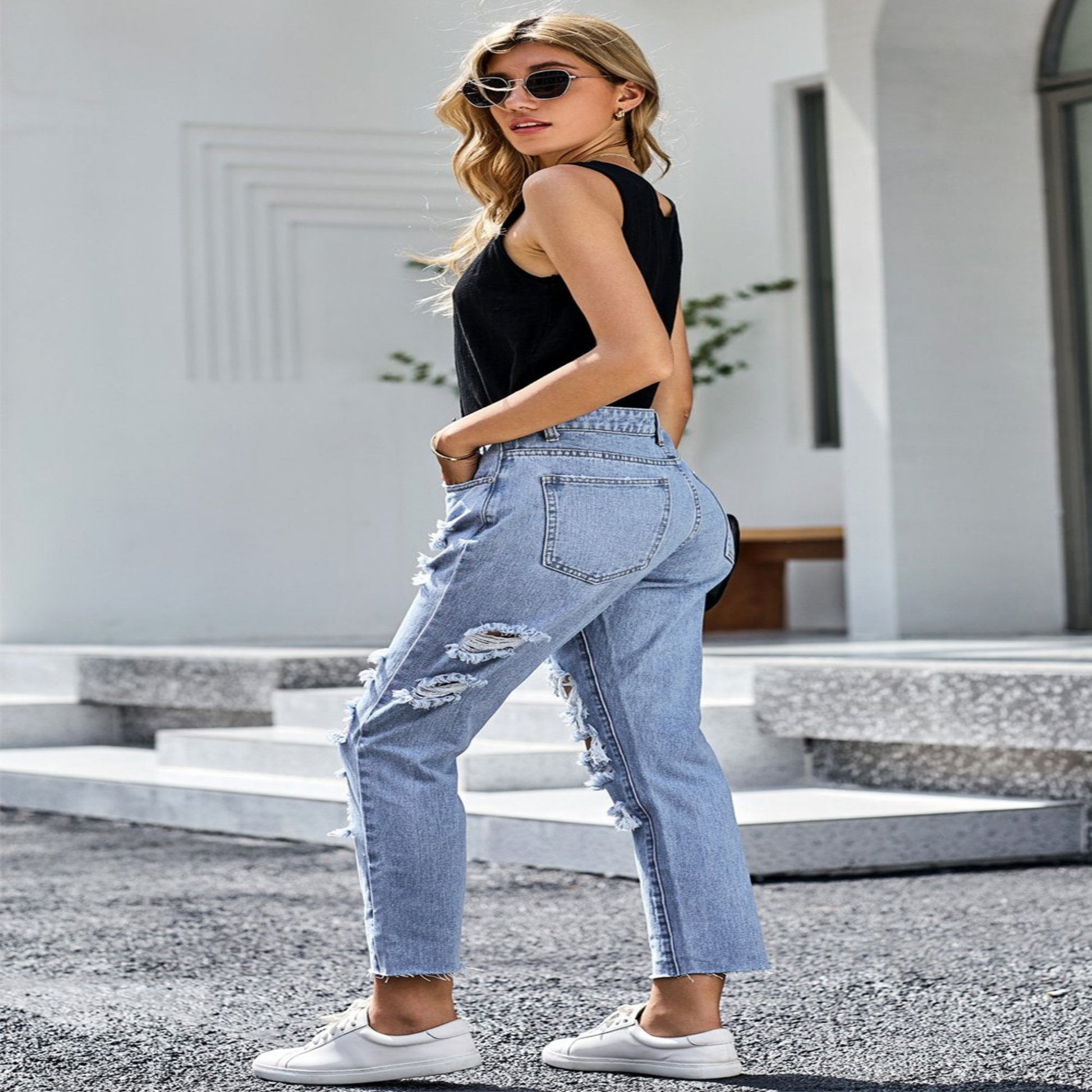 Woman wearing light blue jeans and a black top outdoors.