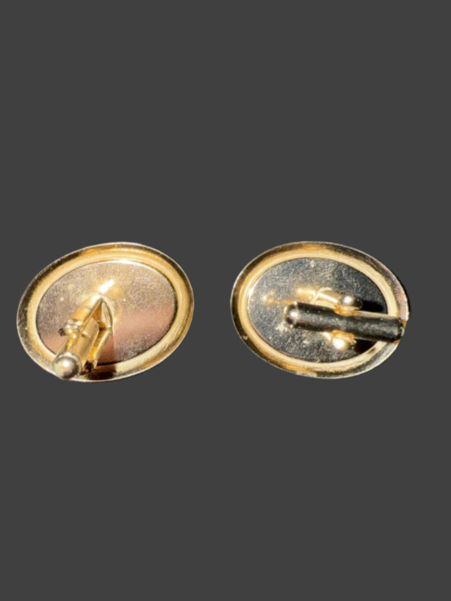 Pair of gold cufflinks on a textured black surface