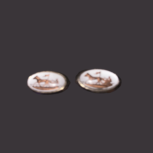 Pair of earrings with white stone and gold accents on a dark background